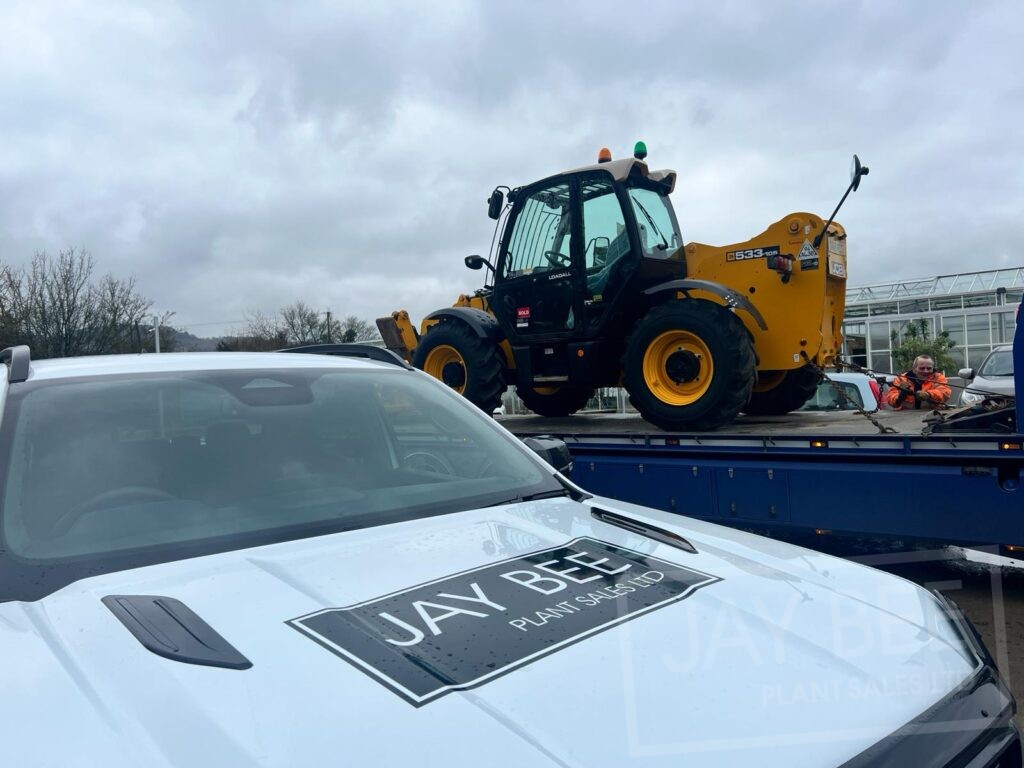 JCB telehandler on a low loader the Jay Bee Plant Sales pick up in the foreground